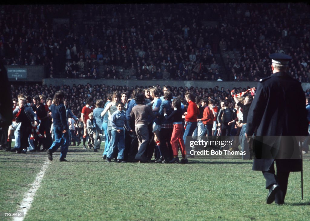 Football. 27th April, 1974. Old Trafford. Manchester United 0 v Manchester City 1. Manchester United fans invade the pitch and mob Manchester City's Denis Law at the final whistle of the Manchester derby. Law scored the only goal of the game to relegate h