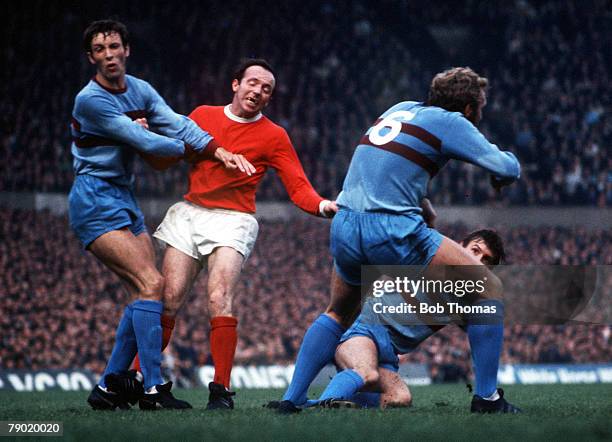 Football, 1970's, Manchester United's Nobby Stiles battles with West Ham's Martin Peters and Bobby Moore during their league match