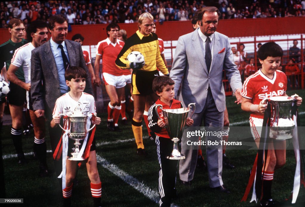 Football. 1983. Young mascots bring out the trophies won by Aberdeen FC and Manchester United in 1983 prior to the testimonial match for United defender Martin Buchan. Pictured left, leading out his side is Aberdeen manager Sir Alex Ferguson who went on t