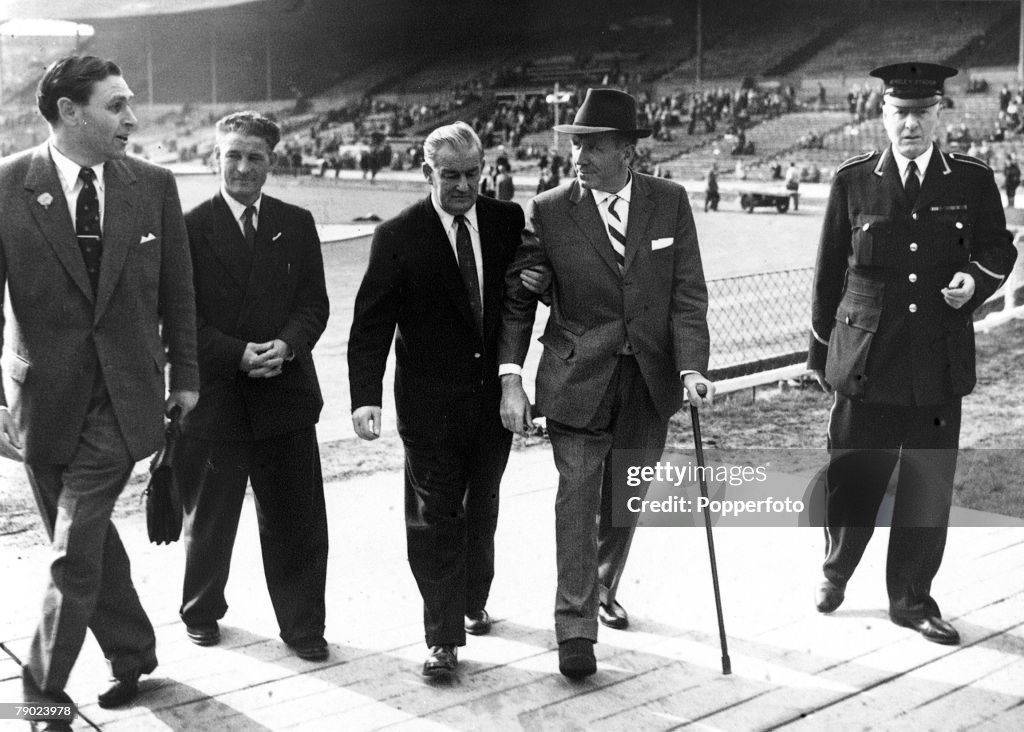 Sport. Football. Wembley, London, England. 3rd May 1958. FA Cup Final. Manchester United 0 v Bolton Wanderers 2. Manchester United Manager Matt Busby is helped back to the dressing room after the match. Busby is still recovering from injuries sustained in