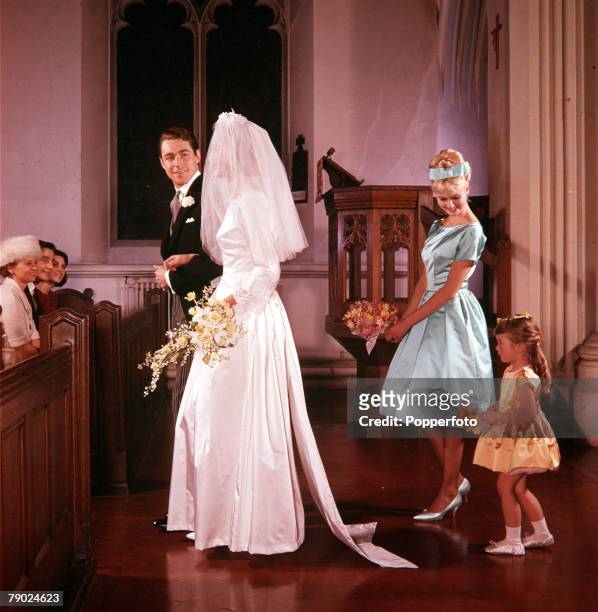 Wedding ceremony in a church with the bride, dressed in an ivory white dress with veil, and groom happily walking away from the alter with two...