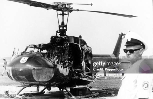 West German Bundesgrenzschutz officer standing guard near a grenade damaged Bell UH-1 helicopter on the day after a gun battle between West German...