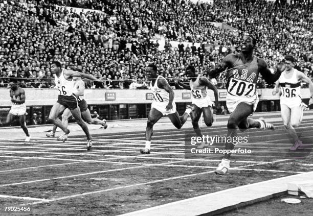 American athlete Bob Hayes crosses the finish line in first place ahead of Harry Jerome of Canada and Enrique Figuerola of Cuba to win the final of...