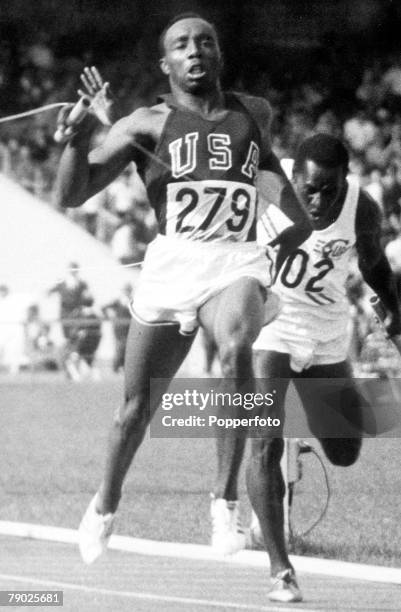 American athlete Jim Hines crosses the finish line ahead of 2nd placed Enrique Figuerola of the Cuba team, for the United States team to win the gold...