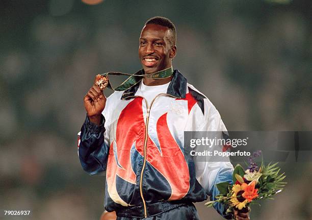 American track athlete Michael Johnson celebrates on the medal podium after finishing in first place in a new world record time to win the gold medal...
