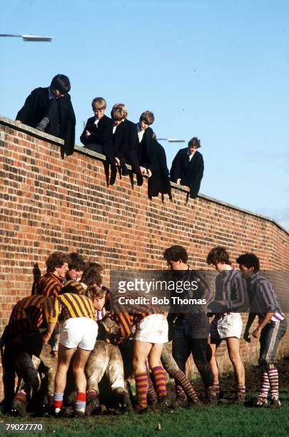 Sport, Eton Wall Game, England, 24th November 1984, Pupils in gowns sit on the wall as they watch the traditional game in progress