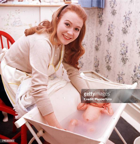 Picture of the British actress Juliet Mills smiling at the camera whilst bathing her baby son Sean