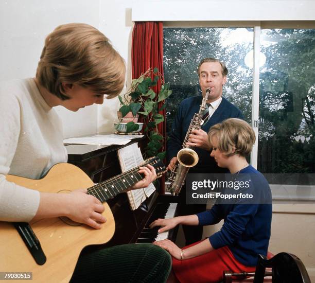Picture of the British actor Ian Carmichael jamming together with his family, playing the saxophone along with accompanied piano and the acoustic...