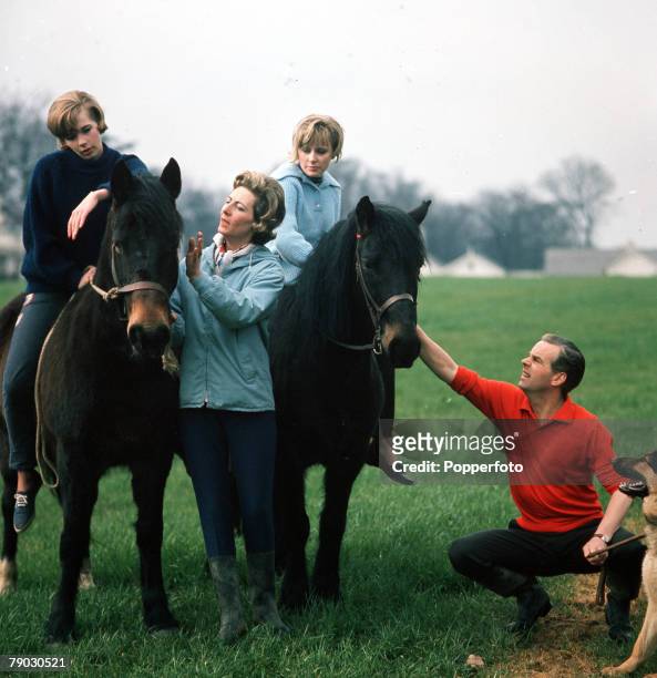 Picture of the British actor Ian Carmichael outside with his family together riding a couple of horses