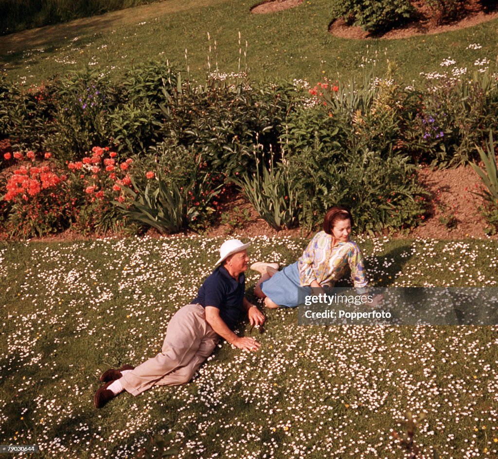 1964 A picture of the American actress Vivien Leigh relaxing with another man outside lying on a lawn full of daisies.