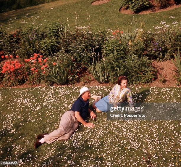 Picture of the American actress Vivien Leigh relaxing with another man outside lying on a lawn full of daisies