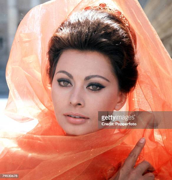 Italian actress Sophia Loren wearing a flowing orange coloured veil, circa 1965.