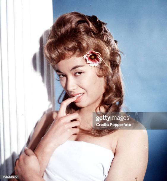 Circa 1960+s, A picture of the Eurasian actress France Nuyen doing an impression of the American beauty Debbie Reynolds wearing a replica of a wig...