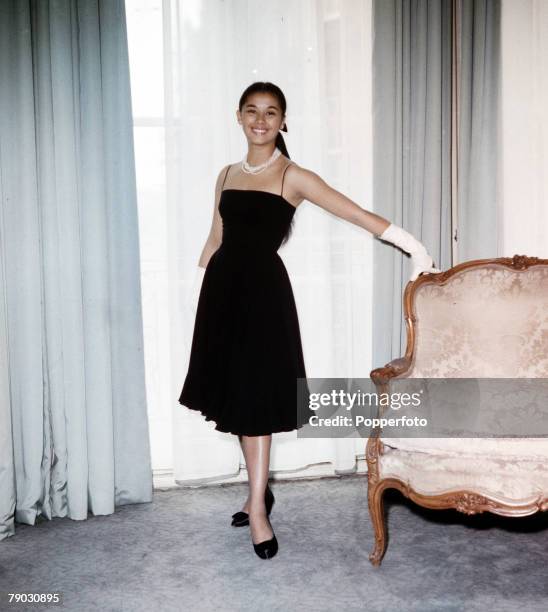 Circa 1960+s, A picture of the Eurasian actress France Nuyen modeling a simple but attractive evening dress in her London apartment