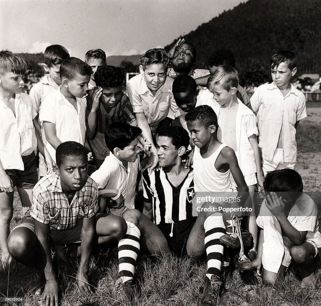 Sport. Football. November 1957. Botafogo and Brazil star Garrincha is pictured sitting with a group of local Brazilian children as he relaxes.