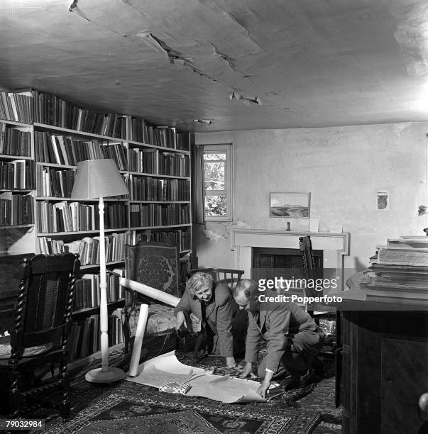 English writer and novelist Agatha Christie studies documents with her husband, archaeologist Max Mallowan , in a library in her home, Winterbrook...