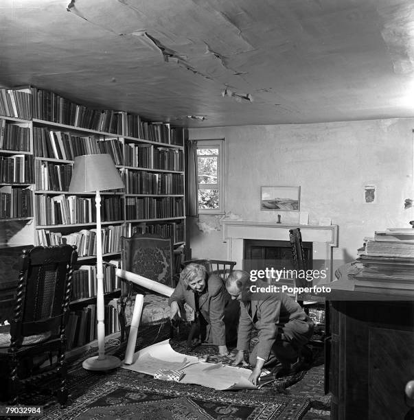 English writer and novelist Agatha Christie studies documents with her husband, archaeologist Max Mallowan , in a library in her home, Winterbrook...