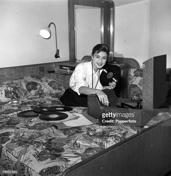 Cinema, London, England French actress Anouk Aimee is pictured playing music on a record player in her room at the Savoy Hotel