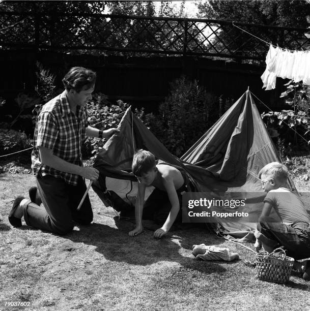 British actor Tony Britton erecting a tent in his garden for two young boys, England, 3rd September 1955.