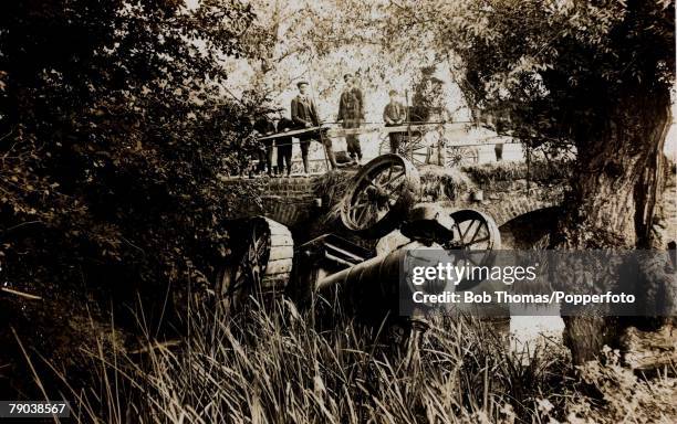 Traction engine upside down in the river as spectators look down at the accident, Grafton Regis,Northamptonshire , circa 1910