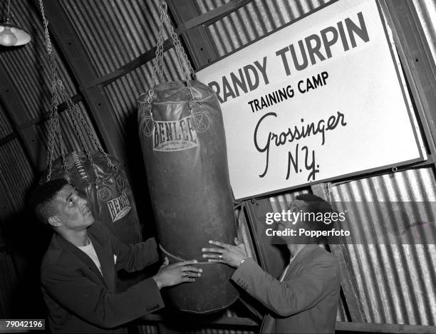 Boxing Grossinger, New York, USA, British boxer Randolph "Randy" Turpin is pictured in the plane hanger which he uses as a gym, fixing a punchbag...