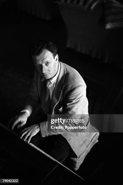 Suffolk, England A portrait of British composer, pianist and condutor Benjamin Britten sitting at his piano at his home at Aldeburgh