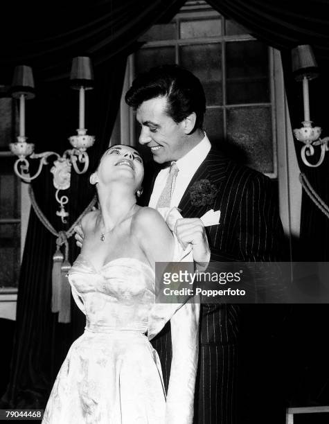 London, England, 25th May 1952, British Actor Maxwell Reed helps his new wife, actress Joan Collins remove the satin bolero style jacket that she...