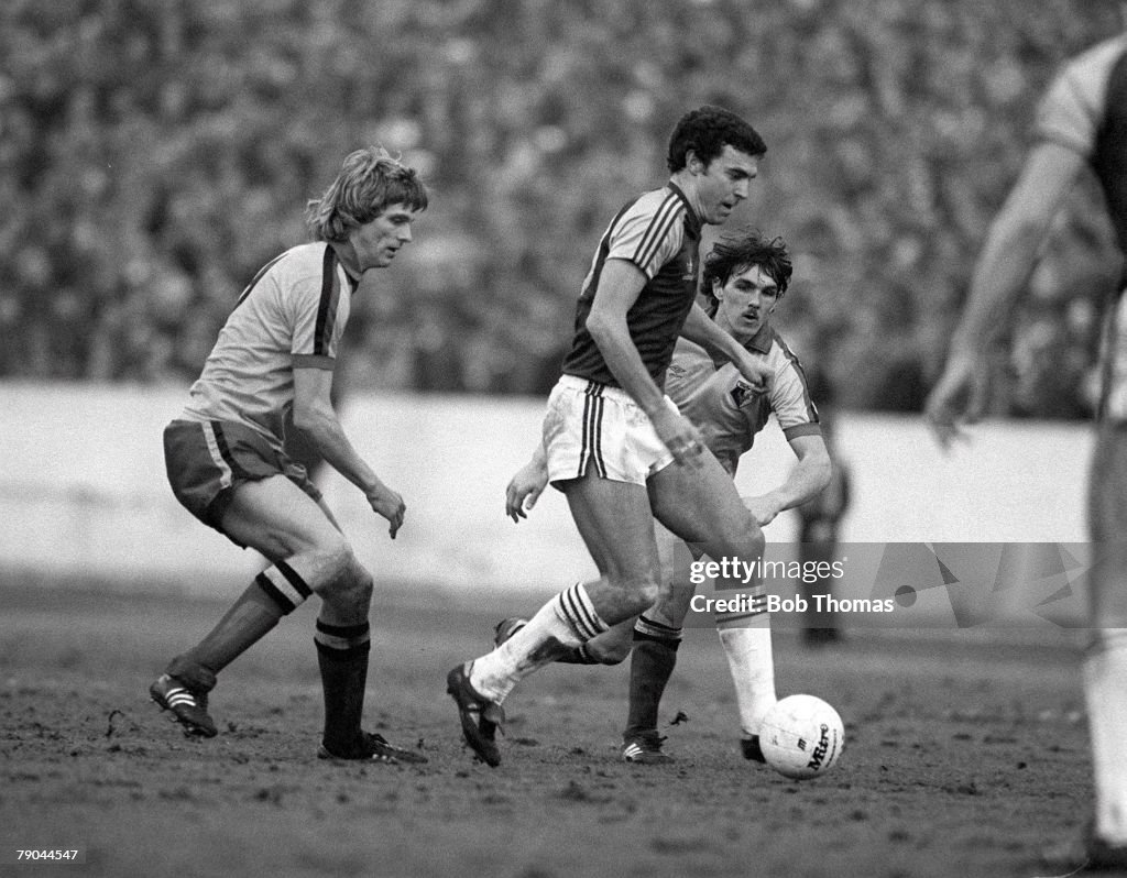 Football. FA Cup 4th Round. Watford, England. 23rd January 1982. Watford 2 v West Ham United 0. West Ham's Trevor Brooking is challenged for the ball by Watford's Ross Jenkins and Jan Lohman.