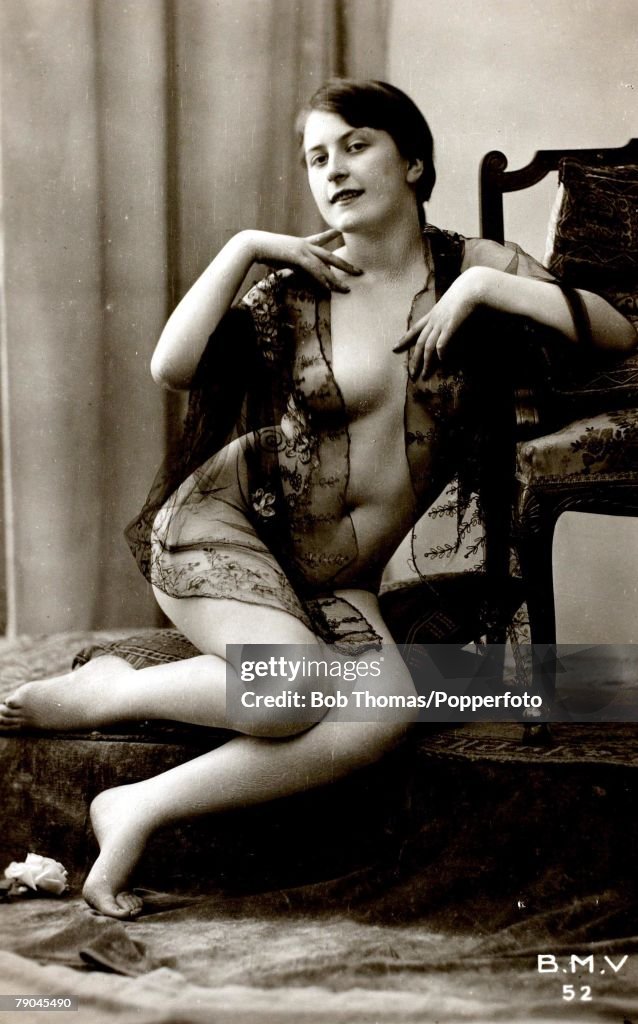 Postcards. Circa 1915. Dishabille. A picture of a woman wearing a black see through wrap whilst sitting posing for the camera.