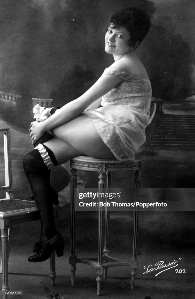 Postcards. Circa 1915. Dishabille. A picture of a woman wearing an undergarment and stockings whilst sitting posing for the camera.