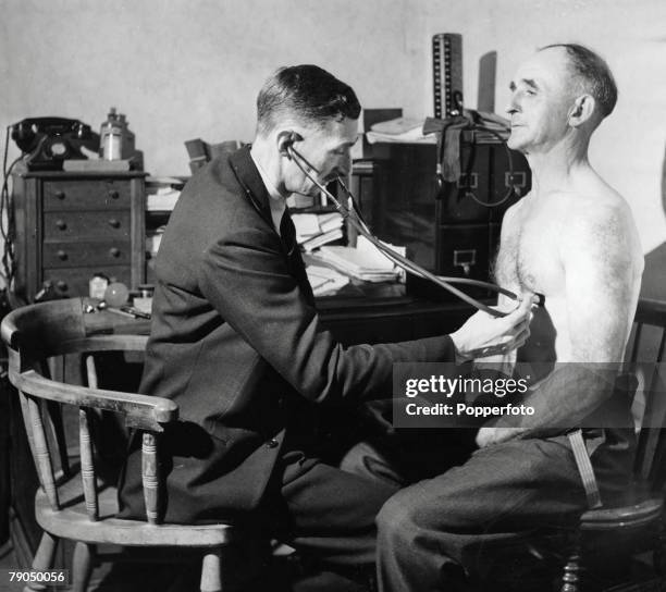 Classic Collection, Page 50 1948, Doctor listening through stethoscope to middle-aged man+s chest: both seated in front of doctor+s desk in GP+s...