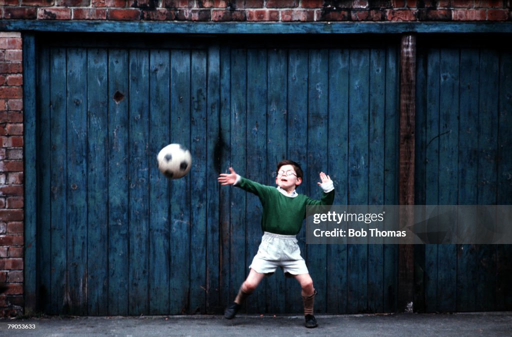 Volume 2, Page 32, Picture,4. 10237021. A young Backstreet goalie, palying a game of football, using the garage door as a goal in the streets of Manchester. Circa: 1970.