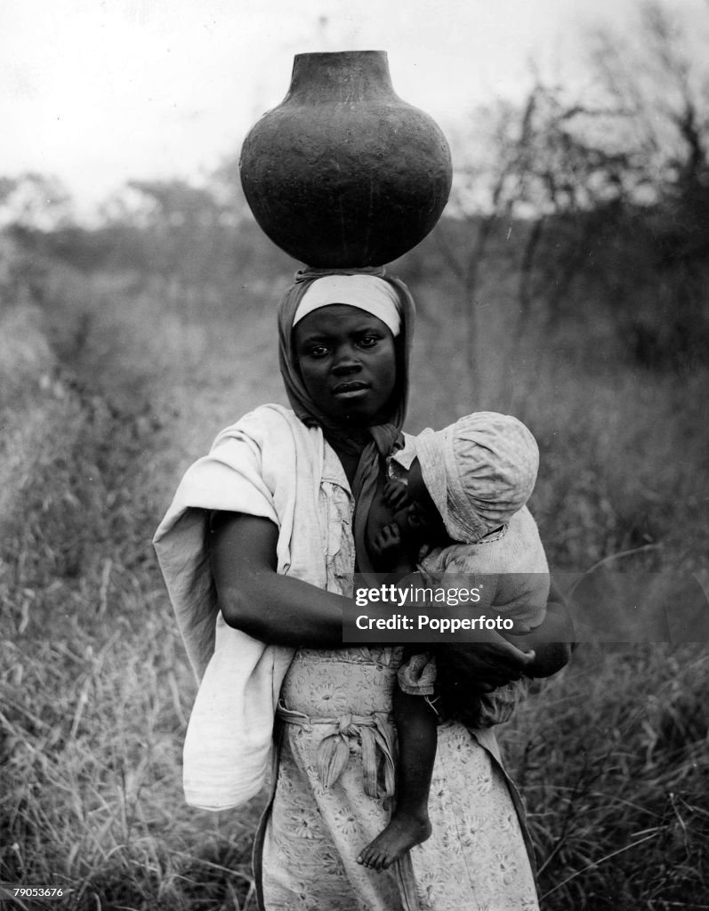 Classic Collection. Page 128. 10423538. Transvaal, South Africa. A black woman holds her suckling baby, with a pot on her head, looking at the camera.