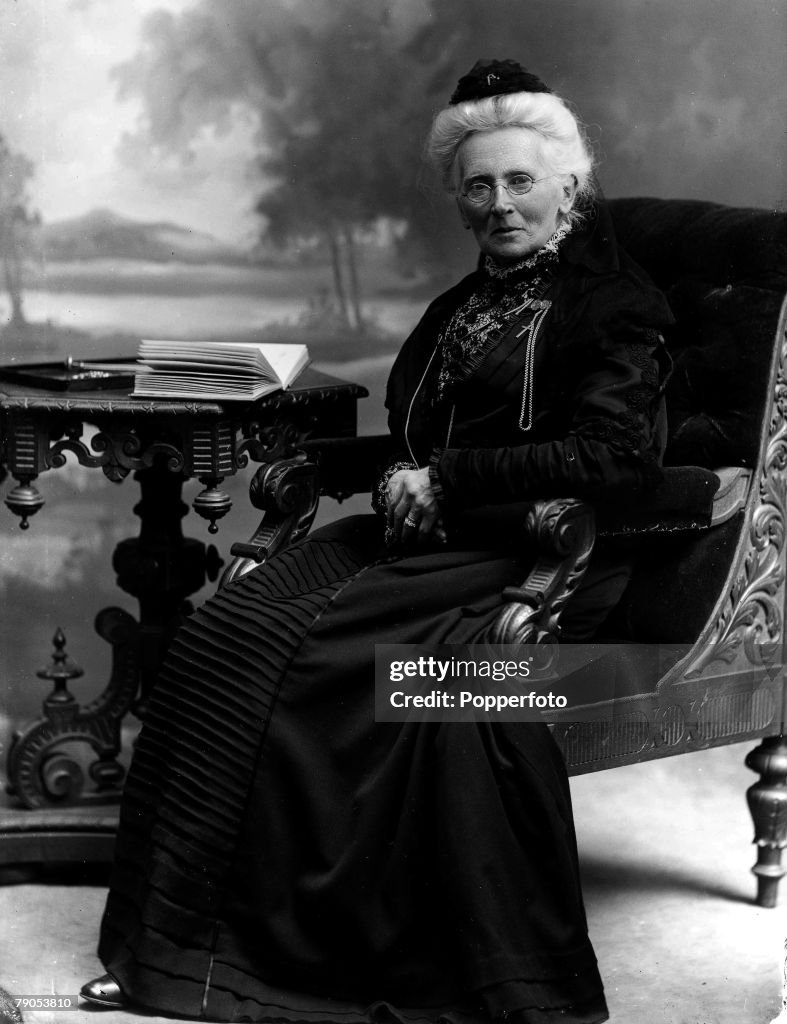 Classic Collection. Page 133. 10425694. Formal portrait of elderly woman seated in ornate wooden chair,woman wearing glasses with book on the table beside her,photographed at the studio of Keswick, Lake District photographer Henry Mayson.