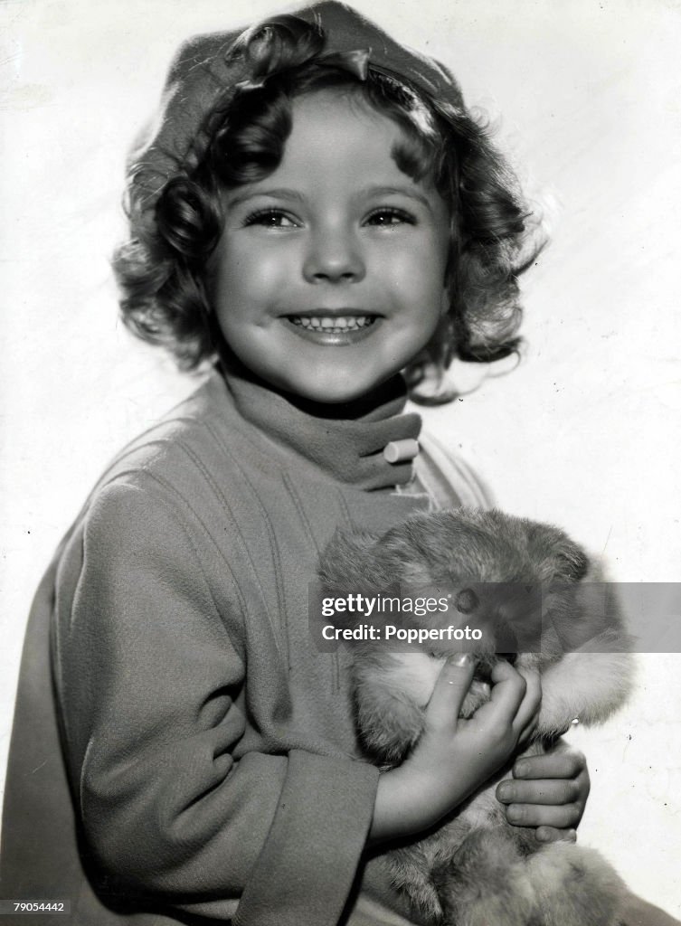 Volume 2. Page 101. Picture 6. Shirley Temple, portrait when a young girl, with a cuddly toy.