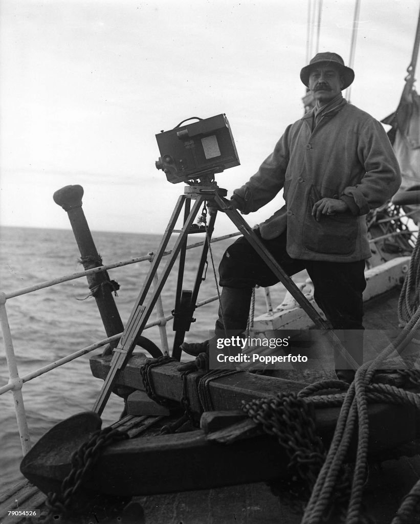 H.G Ponting. Captain Scott+s Antarctic Expedition 1910 - 1912. Photographer Herbert Ponting taking a picture of whales with his camera over the side of the Terra Nova ship