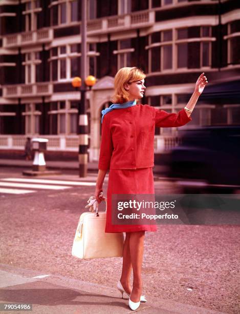 Volume 2, Page 52, Picture 5 London, English model Jean Shrimpton hails a taxicab whilst wearing a red suede suit with cardigan jacket.