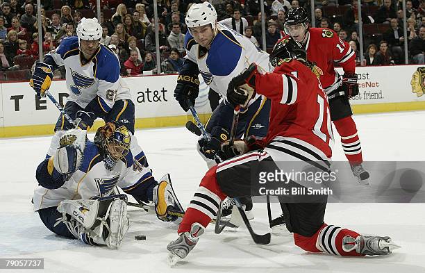 Jack Skille of the Chicago Blackhawks takes a shot against goalie Marek Schwarz of the St. Louis Blues as defender Bryce Salvador stands by on...