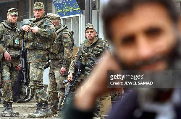 An Afghan man waits for transport as German soldiers of the International Security Assistance Force rest during a patrol in Kabul, 23 February 2003....