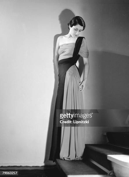 Portrait of an unidentified model in a floor-lemgth Madeleine Vionnet dress, as she stands on a staircase, September 1935.