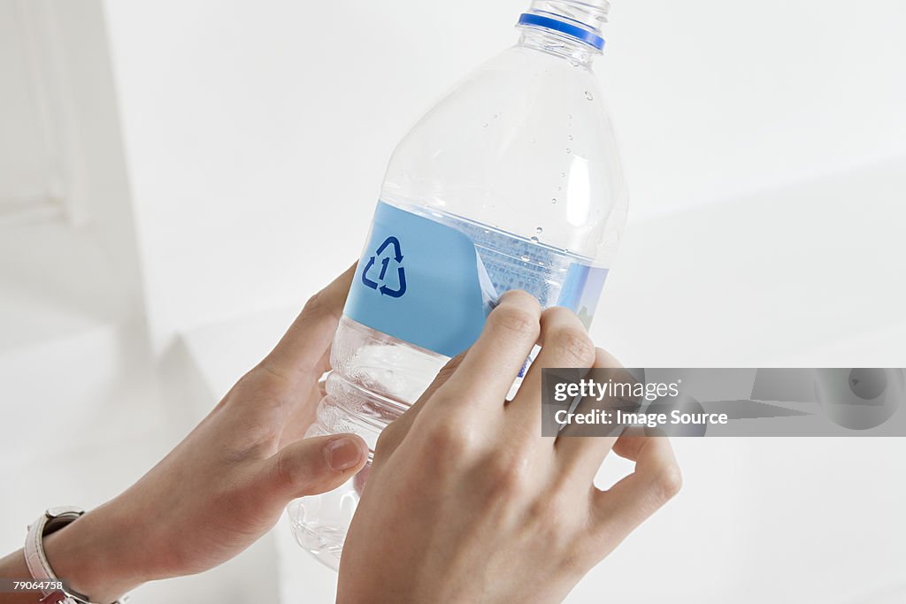 A person peeling off a label off a bottle