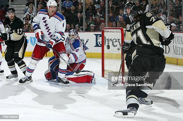 Evgeni Malkin of the Pittsburgh Penguins bats the puck out of the air toward the net as Marek Malik and Henrik Lundqvist both of the New York Rangers...