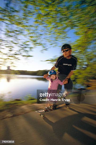 a dad with daughter on a long-board. - father longboard stock-fotos und bilder