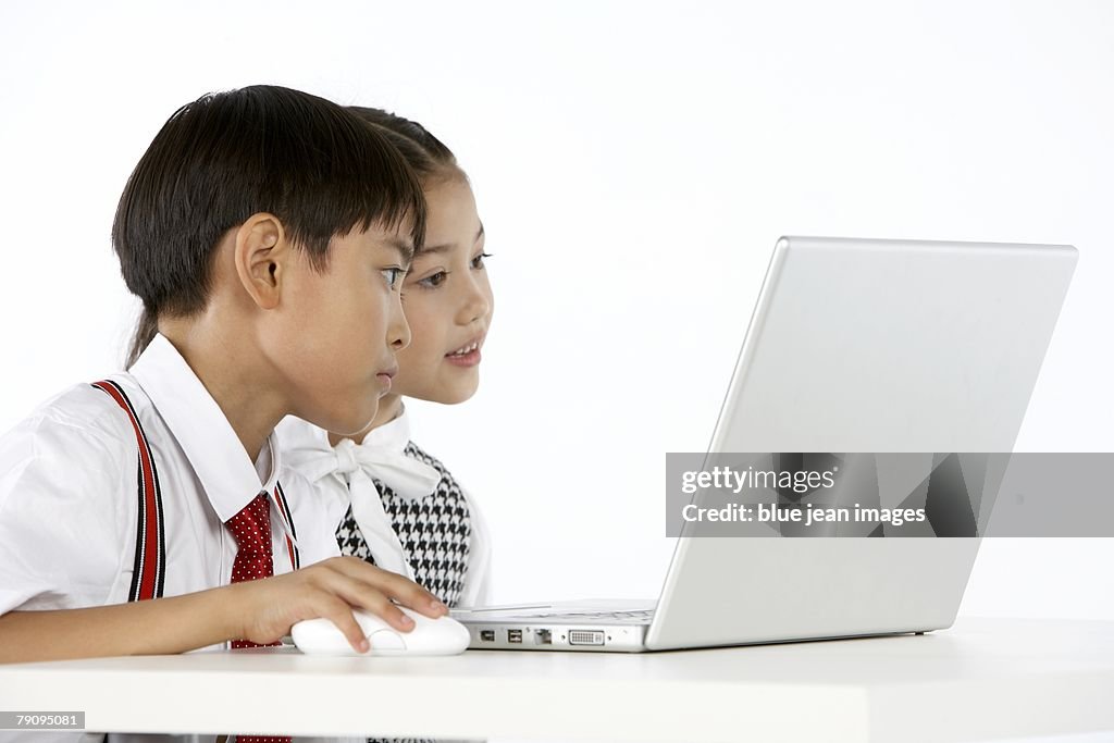 Two children dressed in business attire using their laptop computer.