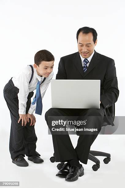 a boy dressed in business attire reviews the contents of a businessman's laptop computer. - stereotypically upper class stock pictures, royalty-free photos & images