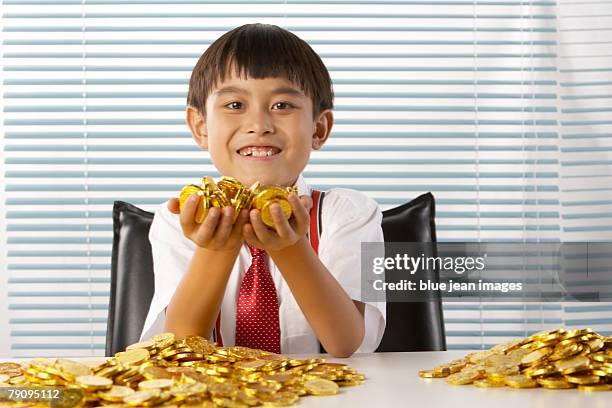 portrait of a boy dressed in business attire holding gold coins. - stereotypically upper class stock pictures, royalty-free photos & images