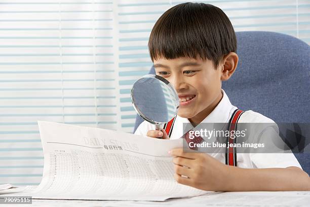 a  young man dressed in business attire checks the business section of the newspaper with a magnifying glass. - stereotypically upper class stock pictures, royalty-free photos & images