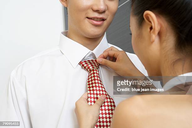 a young woman helps a young man with his tie. - adjusting blue tie stock-fotos und bilder
