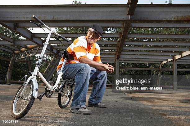 a stylish young man with his bike in an abandoned industrial area. - asian rapper stock pictures, royalty-free photos & images