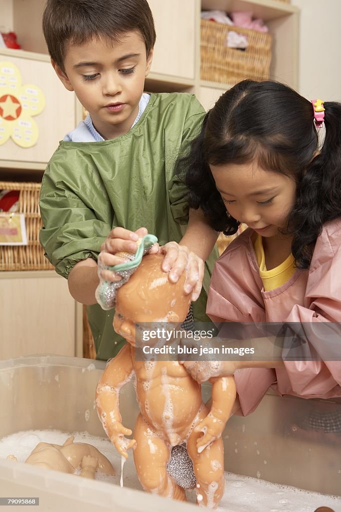 Two children giving their dolls baths at kindergarten.